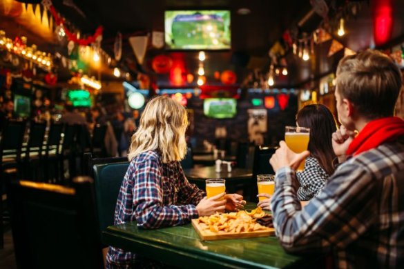 people eating a meal with beers watching sport on a pub screen